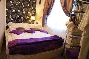 - une chambre avec un lit doté de draps violets et une fenêtre dans l'établissement Hana Apartments, à Subotica