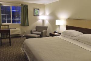 a hotel room with a bed and a chair and a window at Hilltop Inn by Riversage in Billings