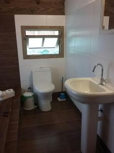 baño con aseo y lavabo y ventana en Casa de Lenir, en Garopaba
