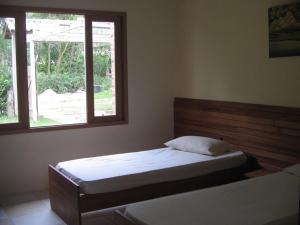 1 dormitorio con 2 camas y ventana en Casa de Lenir, en Garopaba