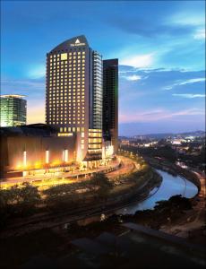 um horizonte da cidade à noite com um rio e edifícios em The Gardens – A St Giles Signature Hotel & Residences, Kuala Lumpur em Kuala Lumpur