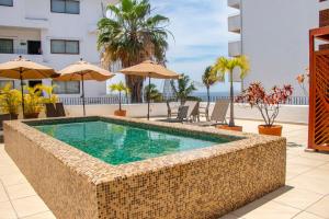 una piscina en un complejo con sillas y sombrillas en Amapas Apartments Puerto Vallarta - Adults Only, en Puerto Vallarta
