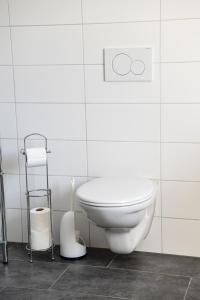 a bathroom with a toilet in a white tiled wall at Königsberger in Ebergötzen