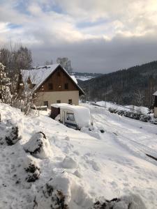 un patio cubierto de nieve con una furgoneta estacionada frente a una casa en Chata Diana, en Vítkovice