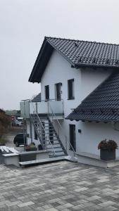 ein weißes Haus mit einer Treppe auf einem Parkplatz in der Unterkunft LUX Ferienwohnungen in Hepbach