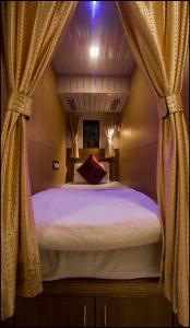 Qubestay Airport Capsule Hotel & Hostel في مومباي: غرفة نوم بسرير كبير مع ستائر