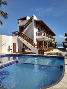 a villa with a swimming pool in front of a house at Pousada e Restaurante Altas Horas Beach in Itapipoca