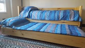 una cama de madera con sábanas azules encima. en Aparments R&G Puerto Montt, en Puerto Montt