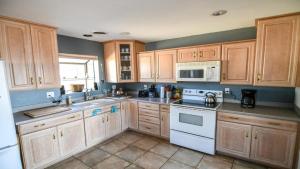 a kitchen with wooden cabinets and white appliances at Hoodoo House - 4-Bedroom Near Lake Powell in Page