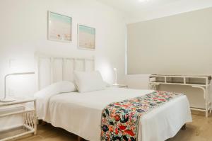 a white bedroom with a bed and two tables at Casita del Mar in Cancún