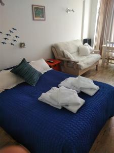 Una cama azul con toallas blancas encima. en Estudio en Edificio Alnes en Mar del Plata
