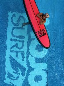 a woman is laying on a surfboard in a pool at Mojosurf Camp Canggu in Canggu