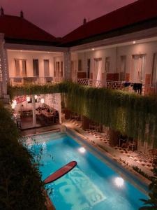 a swimming pool in front of a building at night at Mojosurf Camp Canggu in Canggu