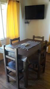 a wooden table with chairs and a television on a wall at Cabañas Las Acacias in San Clemente del Tuyú