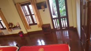 a living room with two red chairs and windows at Villa Kee Lee Hotel 1 in Luang Prabang