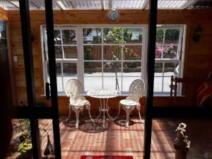 a patio with a table and chairs in front of a window at Ranfurly Cottage in Raetihi