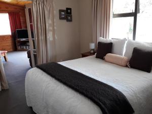 a bedroom with a large bed with a large window at Ranfurly Cottage in Raetihi