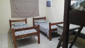 two beds sitting in a room with a window at Hostel Famille Brun Trevo in São João da Boa Vista
