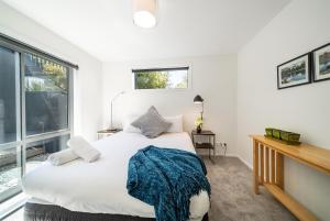 a bedroom with a white bed and a window at Lake View Greenstone Luxe Apartment in Queenstown