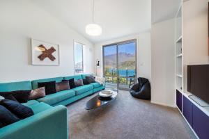 ein Wohnzimmer mit einem blauen Sofa und einem Tisch in der Unterkunft Lake View Greenstone Luxe Apartment in Queenstown