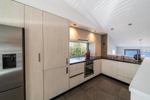 a kitchen with wooden cabinets and a window at Lake View Greenstone Luxe Apartment in Queenstown