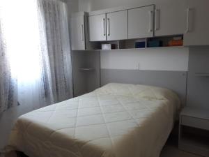 a bedroom with a bed with white cabinets and a window at Praia da Cachoeira in Florianópolis