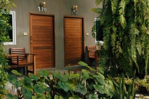 zwei Holztüren an der Seite eines Hauses mit Pflanzen in der Unterkunft Le Pes Villas in Khanom