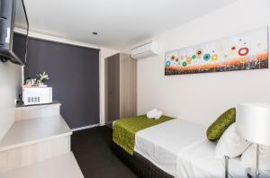 a hotel room with a bed and a painting on the wall at Icon on Isa in Mount Isa