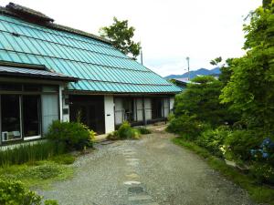 a house with a green roof and a gravel driveway at ゲストハウス『古民家の宿 梨 本 軒』 in Takai