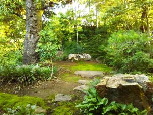 a garden with a stone path and a tree at ゲストハウス『古民家の宿 梨 本 軒』 in Takai