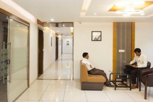 two men sitting in chairs in a hospital lobby at Hotel Royal Shelter in Vapi