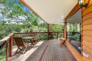 a wrap around deck with a table and chairs on it at Ravensbourne Escape-Tree Tops in Ravensbourne