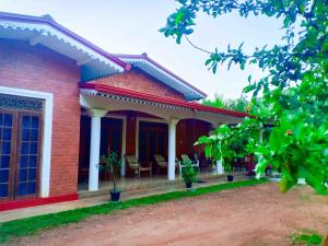 una casa de ladrillo rojo con sillas en el porche en Sigiri Thilanka Rest Sigiriya, en Sigiriya
