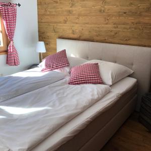 a bed with two red and white pillows on it at Chalet Tirolia in Kirchdorf in Tirol