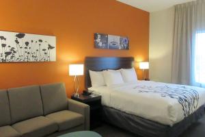 OregonにあるSleep Inn & Suites Oregon - Madisonのベッドとソファ付きのホテルルーム