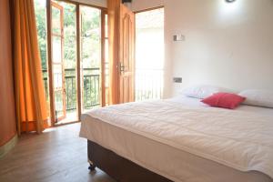 a bedroom with a large bed and a large window at White Villa Kitulgala in Kitulgala