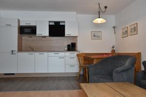 een keuken met witte kasten en een tafel en een stoel bij Haus Prieth in Nauders +10 foto's