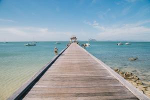 a wooden pier leading into the water with boats at Santhiya Koh Yao Yai Resort & Spa in Ko Yao Yai