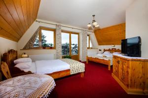 a bedroom with two beds and a flat screen tv at Zakopiański Dwór in Zakopane