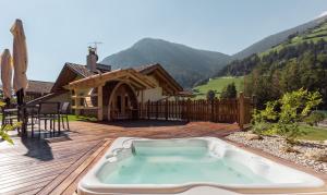 una bañera de hidromasaje en una terraza con una casa en Hotel Appartement Haus Gitschberg, en Vandoies