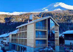 a building with a car in front of a mountain at Montivas Lodge in Livigno