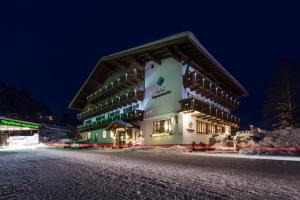 a large building on a snowy street at night at Hotel Aquamarin in Bad Mitterndorf