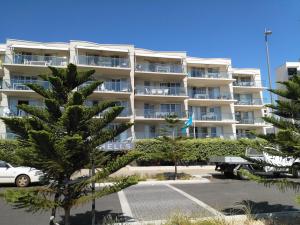 a large white apartment building with trees in a parking lot at Salty Kiss in Perth