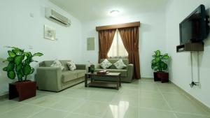 un soggiorno con divani e TV a schermo piatto di La Villa Inn Hotel Apartments a Doha