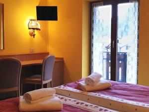 a bedroom with a bed and a desk and a window at Hotel Etoile De Neige in Valtournenche