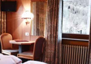 um quarto de hotel com uma mesa e uma janela em Hotel Etoile De Neige em Valtournenche