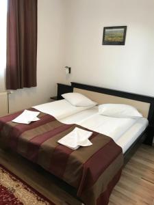 a bedroom with a large bed with two white pillows at Farkas Panzió in Cîrţa +31 photos