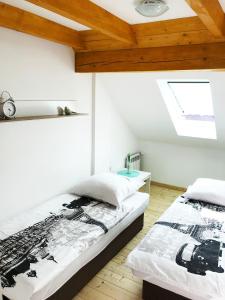 two beds in a room with white walls and wooden ceilings at Apartamenty Centrum Rajcza in Rajcza