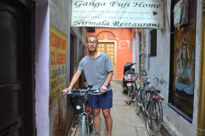 a man is standing with his bike in an alley at Ganga Fuji Home in Varanasi