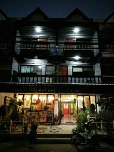 ein Gebäude mit einem Motorrad, das nachts davor geparkt ist in der Unterkunft Tangmo House in Chiang Mai